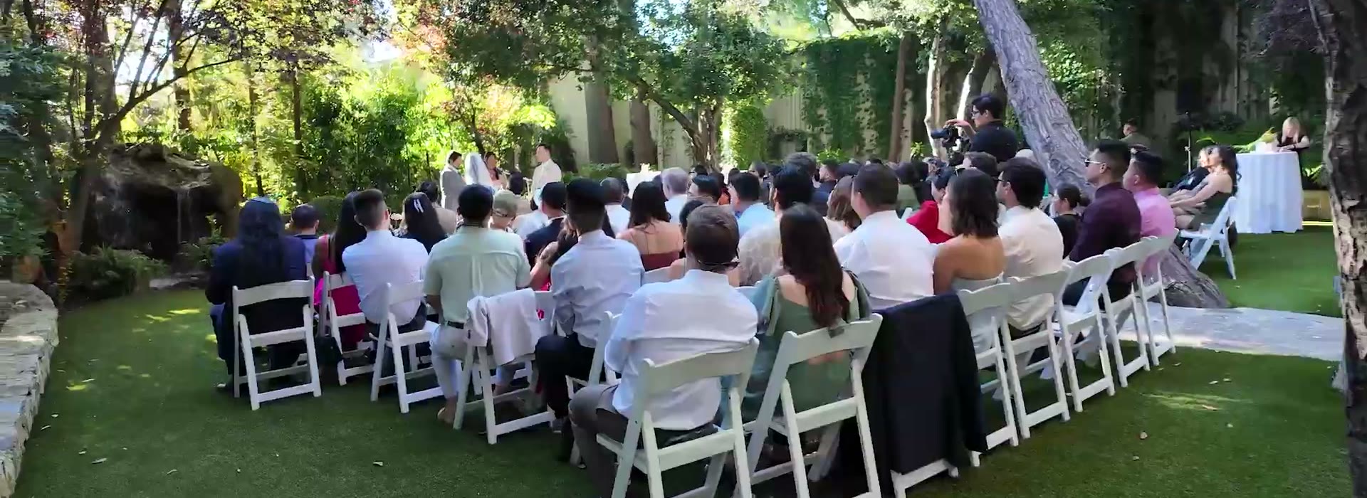 An outdoor wedding ceremony set under the oak canopy at Calamigos Ranch in Malibu, guests seated on white chairs
