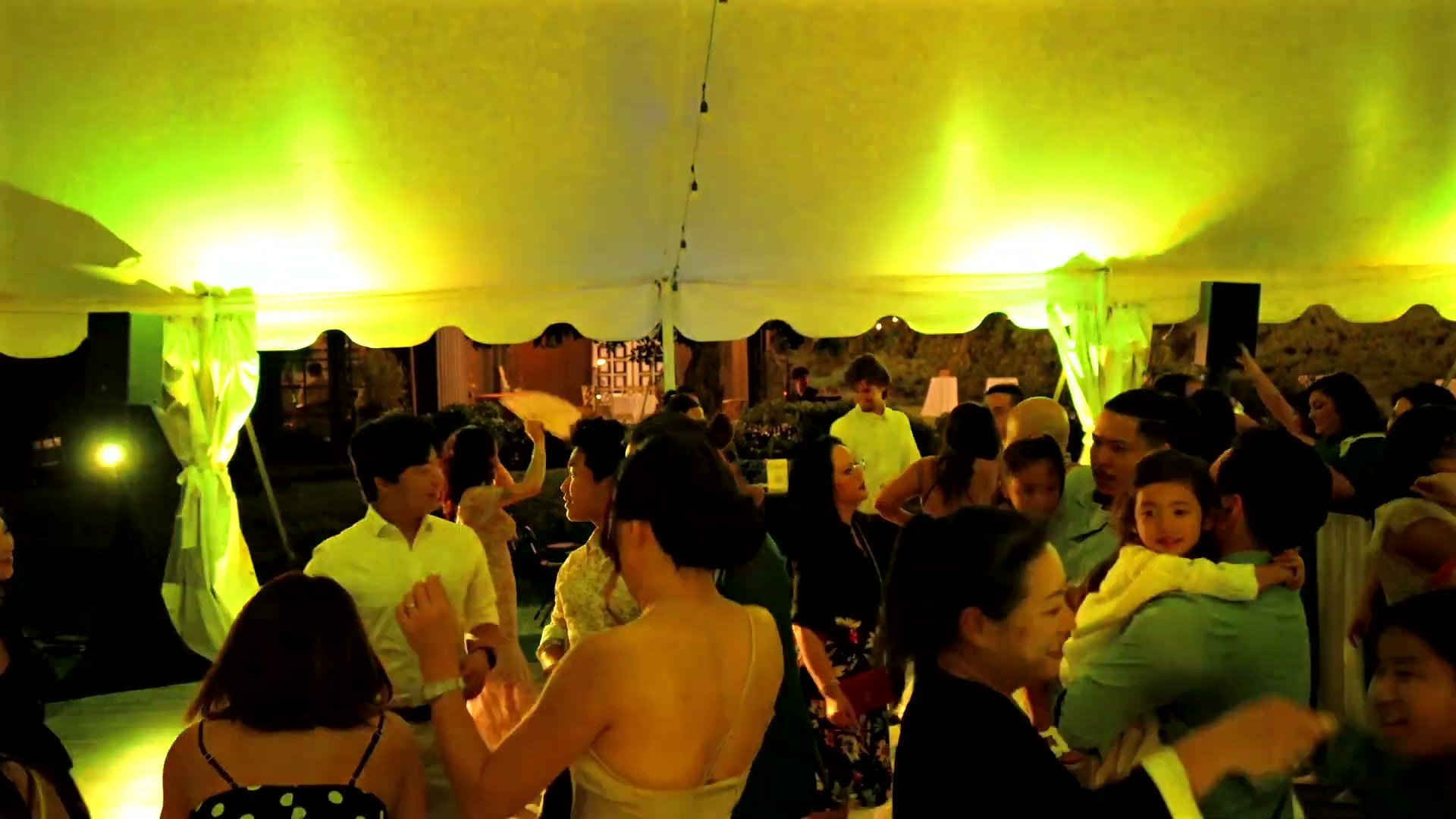 Packed reception tent glowing with uplighting at Ethereal Gardens