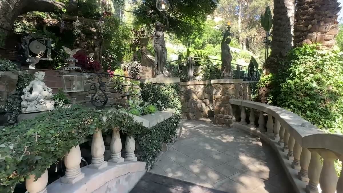 Garden path lined with statues and palms at the Houdini Estate in Los Angeles