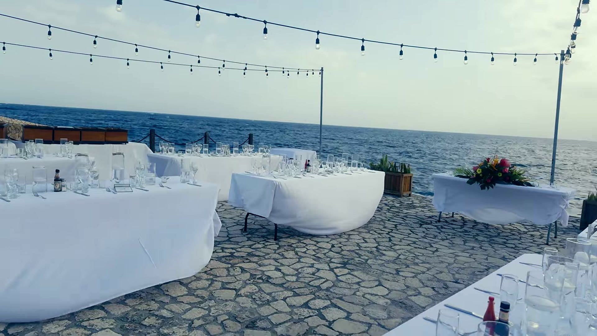 Wedding dinner tables set on the cliffs at Rockhouse Hotel in Negril, Jamaica, under string lights