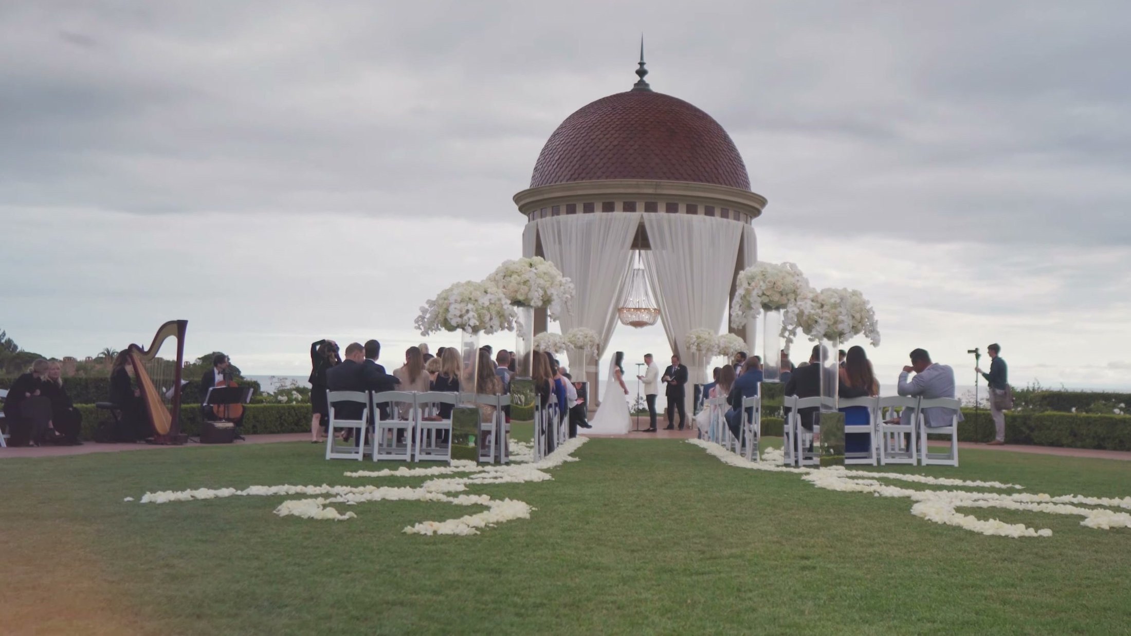 Ceremony at the Pelican Hill rotunda with a petal-lined aisle and a harpist playing